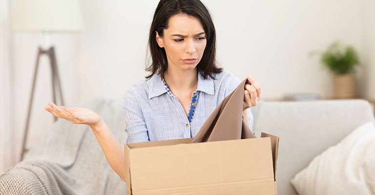 Donna scontenta del vestito che tira fuori da uno scatolone