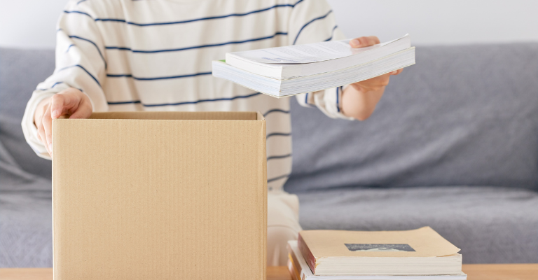 Persona che mette libri in uno scatolone
