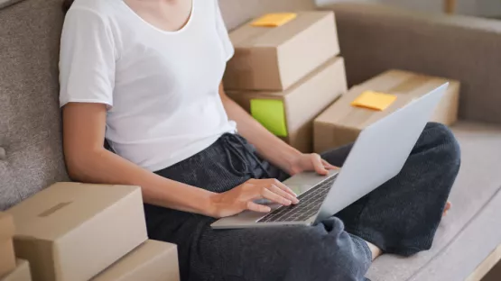 Persona seduta sul divano a gambe incrociate che guarda il pc 