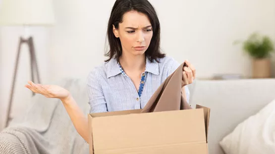 Donna scontenta del vestito che tira fuori da uno scatolone