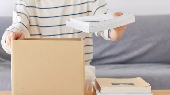 Persona che mette libri in uno scatolone