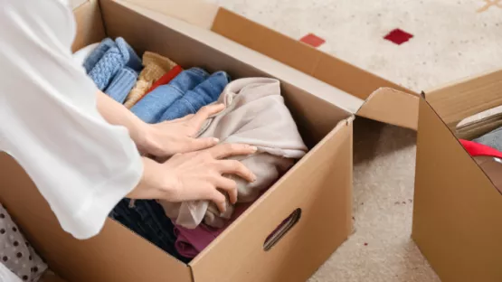 Persona che mette vestiti in uno scatolone per spedirli