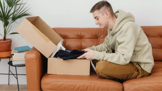 Ragazzi che inserisce in una scatola dei vestiti