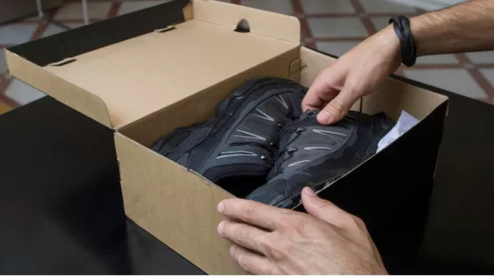 Persona che sta mettendo delle scarpe dentro una scatola
