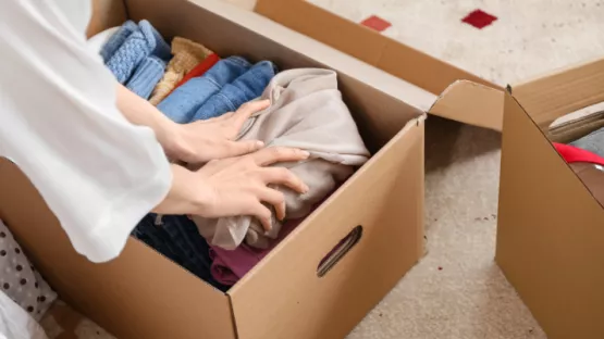 Persona che posiziona vestiti in una scatola