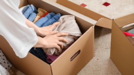 Persona che posiziona vestiti in una scatola