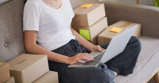 Persona seduta sul divano a gambe incrociate che guarda il pc 
