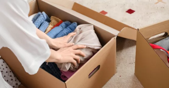 Persona che mette vestiti in uno scatolone per spedirli