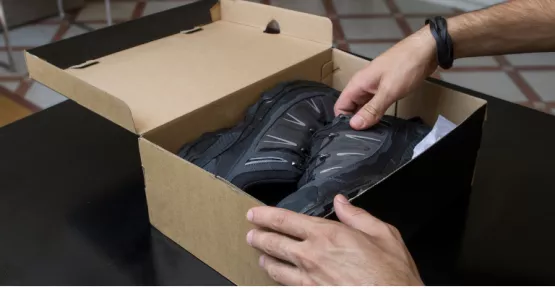 Persona che sta mettendo delle scarpe dentro una scatola